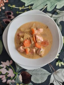 La zuppa di salmone finlandese in un piatto bianco. La zuppa è di colori vivaci caatterizzati dalle carote, il salmone, e la panna.