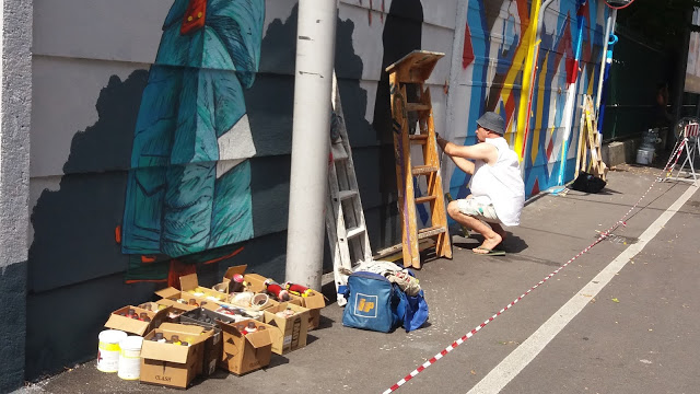 Un writer al lavoro sul Corso Milano a Padova. Inginocchiato dipinge su un muro di cemento, con 40 gradi e 88 per cento di umidità, una giornata estremamente calda di Agosto